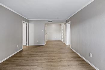 A long, empty hallway with wood flooring and white walls.